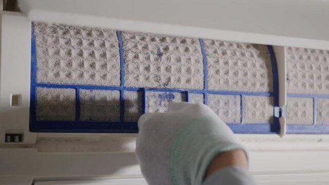 Person removing air conditioner filter, Hand of technician man working pulling dusty filter from air conditioner to cleaning in the room at home