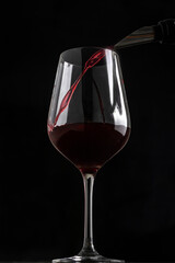 pouring wine into a glass with a black background