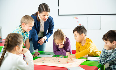 Teacher and pupils play a table game in elementary school class