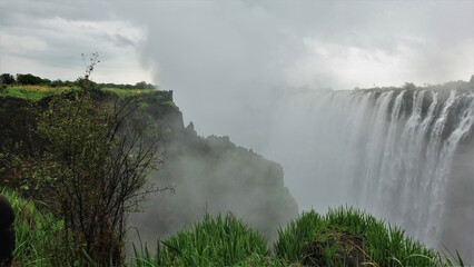 Powerful streams of water fall into the gorge. A dense fog stands over the abyss. Tiny silhouettes...