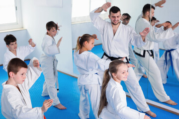 Smiling children attempting to master new moves during karate class.