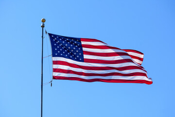 USA Flag. Flag of the United States flying waving beautifully on a pole in the wind. Blue sky