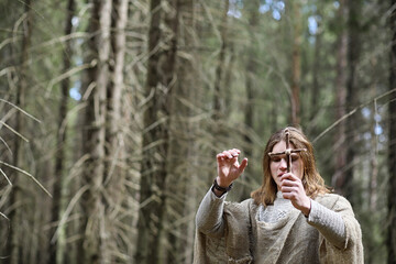 A man in a cassock spends a ritual in a dark forest