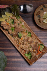 Pork fried rice with broccoli and carrots on wooden background.