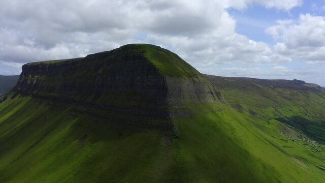 Benbulbin Mountain Sligo, Ireland, June 2021. Drone orbits the south and eastern faces as shadows shroud the slopes ascending to reveal Benwiskin and the Gleniff Horseshoe mountains in the background.