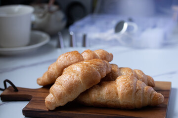 croissant on a brown plate next to a mug of milk on marble background
