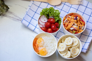 Take away healthy food in foil boxes on marble table.