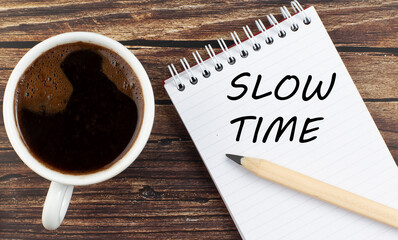 SLOW TIME text on notebook with coffee on wooden background