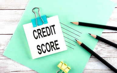 Text CREDIT SCORE on the short note with pencils on the wooden background
