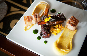 Gourmet plate of pork ribs, bacon in chickpea hummus