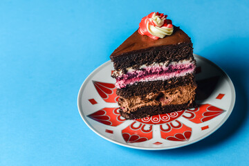 Chocolate cherry cake on a colorful plate over blue background.