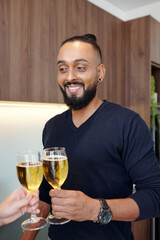 Portrait of handsome bearded man clinking glasses with girlfriend when they are celebrating anniversary at home