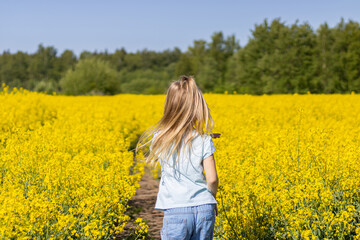 Fototapeta premium Litlle Girl Running Through Yellow Field. Nature background. Childhood. 