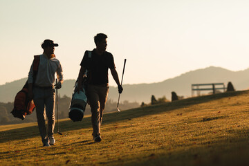 silhouette of golfers who walking and carrying golf bags in warm sunshine. leisure and sport...