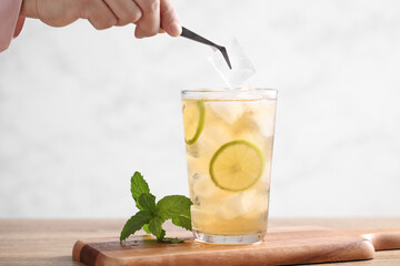 Food stylist use tweezers decorating iced tea with lemon