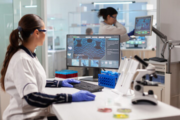 Healthcare researcher working to discover a vaccine working on computer. Scientists examining vaccine evolution in medical lab using high tech, chemistry tools for scientific research.