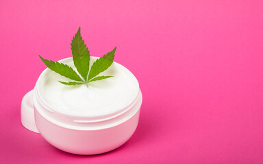 Obraz na płótnie Canvas cosmetic skin care cream with hemp extract on pink background copy space