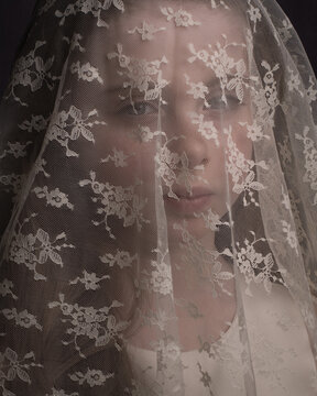 Close up studio portrait of a girl with lace veil like a bride