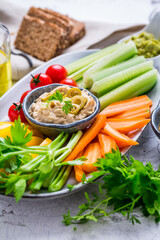 Platter of assorted fresh vegetables with avocado dip, hummus, marinated mushrooms