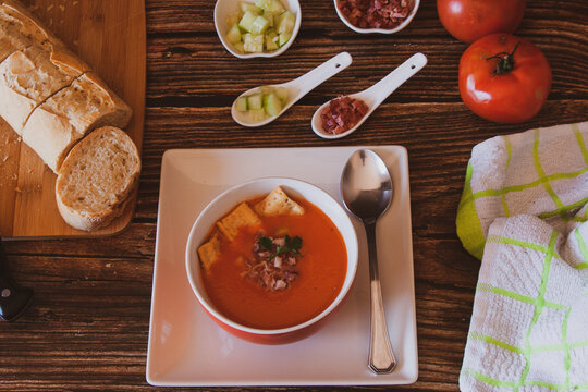 Gazpacho andaluz con unos tacos de pepino, jam&oacute;n y biscotes de pan.