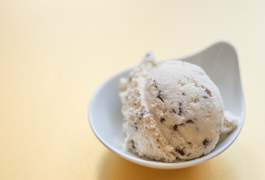 selbstgemachtes Stracciatella Eis mit Ahornsirup, Schokolade mit Kokosbl&uuml;tenzucker, Hintergrund gelb