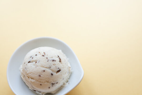 selbstgemachtes Stracciatella Eis mit Ahornsirup, Vanilleschote, Schokolade mit Kokosblütenzucker, Hintergrund gelb