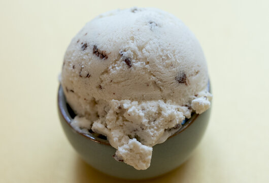 selbstgemachtes Stracciatella Eis mit Ahornsirup, Vanilleschote, Schokolade mit Kokosbl&uuml;tenzucker, Hintergrund gelb