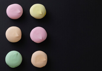 Colorful tasty marshmallows on black background with copy space on the right. Top view.