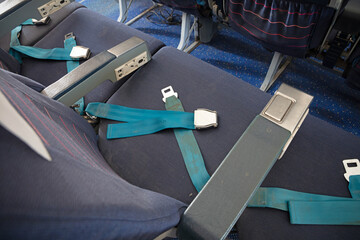Opened seat belt in an old airplane with empty seat - Security concept