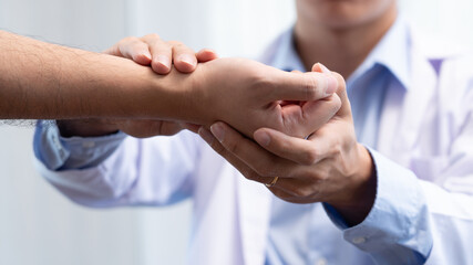 Medical concept a male doctor diagnosing a male patient’s wrist by pressing the wrist bone