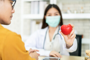 Asian expertise cardiologist doctor showing a beautiful red heart shape to the camera.