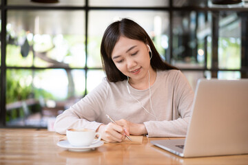 Beautiful Asian young businesswoman working at co-working space in coffee shop.