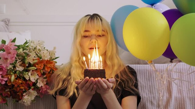 Birthday of female teenager, girl with birthday small cake with burning candles, blowing out the candles