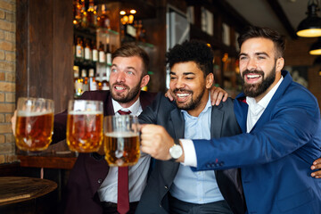 Men fans screaming and watching football on TV and drink beer in a pub