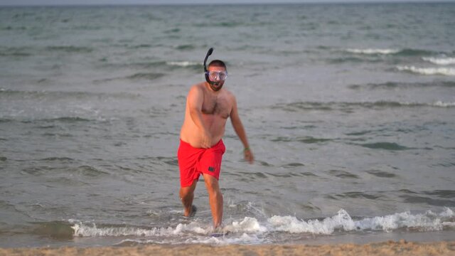 Chubby man inside the sea with diving goggles and snorkel