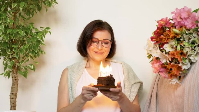 Mature beautiful woman with small birthday cake with burning candles