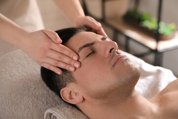 Fototapeta na wymiar Man receiving facial massage in beauty salon, closeup