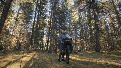 Obraz premium The woman travel on mixed terrain cycle touring with bike bikepacking outdoor. The traveler journey with bicycle bags. Stylish bikepacking, bike, sportswear in green black colors. Magic forest park.