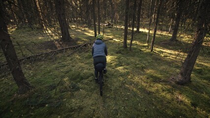 The woman travel on mixed terrain cycle touring with bike bikepacking outdoor. The traveler journey with bicycle bags. Stylish bikepacking, bike, sportswear in green black colors. Magic forest park.