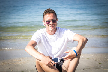 relaxed man on the beach with headphones and mobile phone