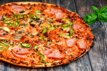  Close up of    hot italian pizza   classic ham. Fresh basil,tomato sauce ,mozzarella cheese , mushrooms and  minced meat .Concept poster for Restaurants or pizzerias. Top view