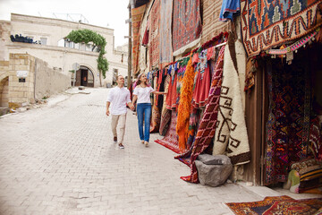 Obraz na płótnie Canvas Couple in love buys a carpet and handmade textiles at an oriental market in Turkey. Hugs and cheerful happy faces of men and women