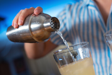 The bartender prepares a cocktail at home. Step five: pour the cocktail into a glass