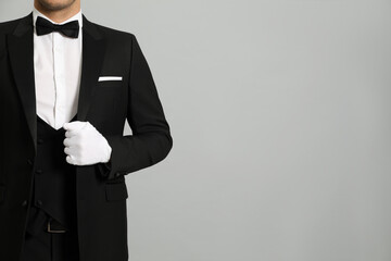 Obraz na płótnie Canvas Butler in elegant uniform on grey background, closeup. Space for text