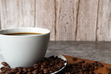 Cup of coffee and coffee beans on old wooden background