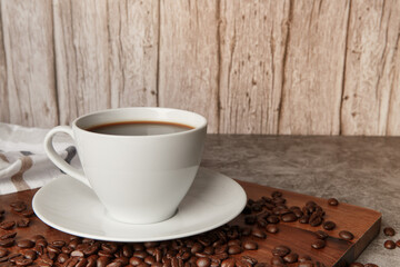 Cup of coffee and coffee beans on old wooden background