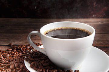 Cup of coffee and coffee beans on old wooden background