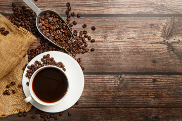 Cup of coffee and coffee beans on old wooden background