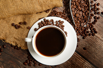 Cup of coffee and coffee beans on old wooden background