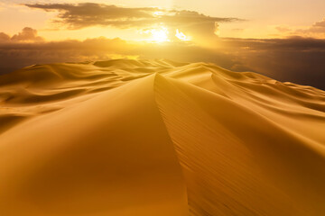 Sunset over the sand dunes in the desert. Arid landscape of the Sahara desert.